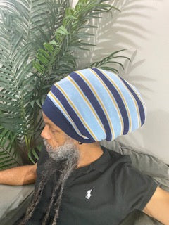 A person with locs wearing a striped stretch hat in blue and white colors.