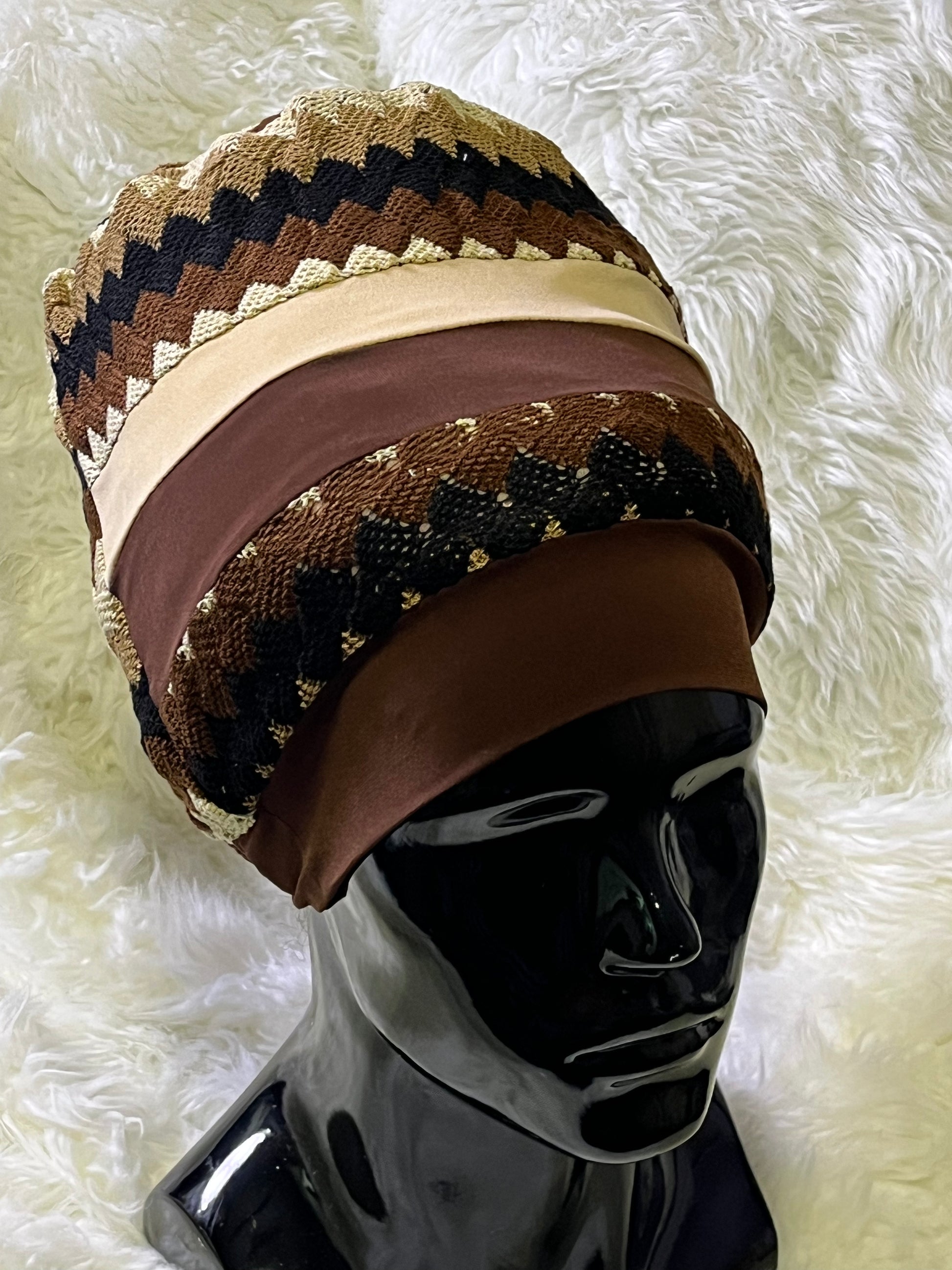 A stretch fabric hat with a flat top and a 2-inch band, featuring a pattern with stars and stripes in earthy tones, displayed on a mannequin head.